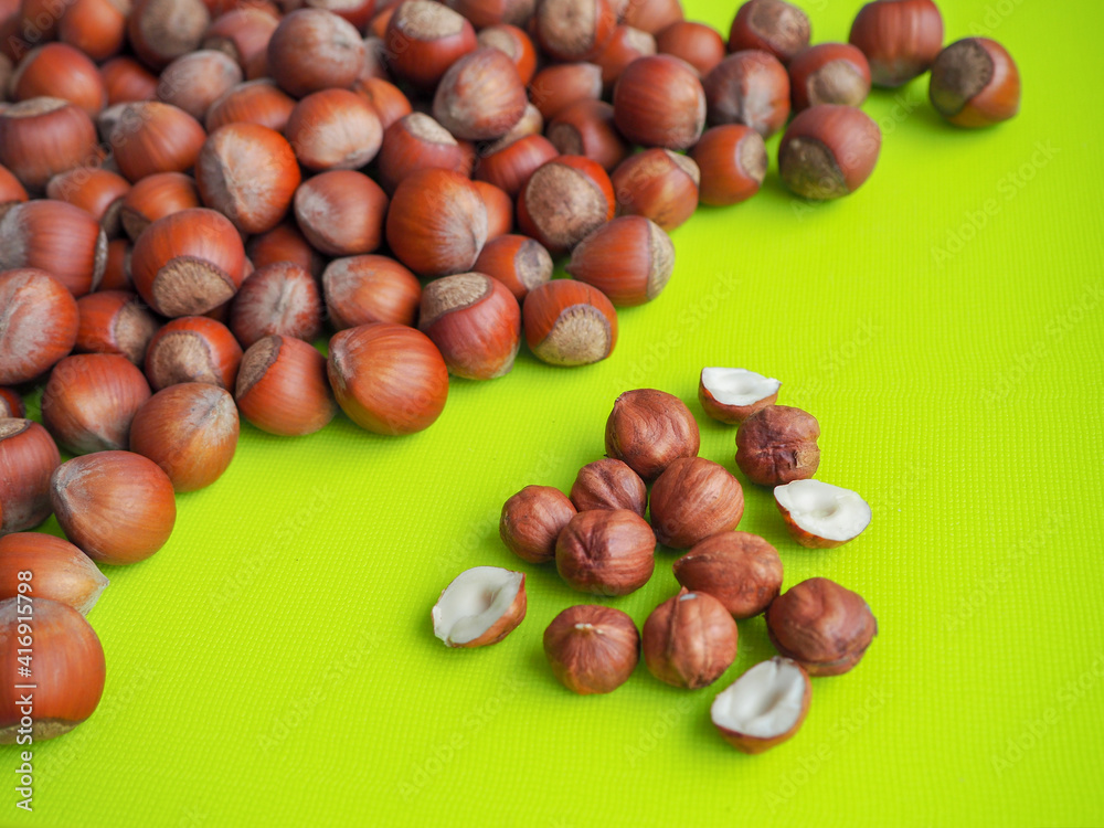 a small handful of peeled hazelnuts near a pile of nuts in the shell a small handful of peeled hazelnuts near a pile of nuts in the shell