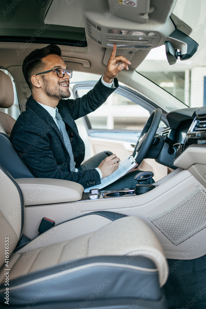 Car seller working in showroom and quality control checking of car details for the last time before buyer comes. Car seller working in showroom and quality control checking of car details for the last time before buyer comes.