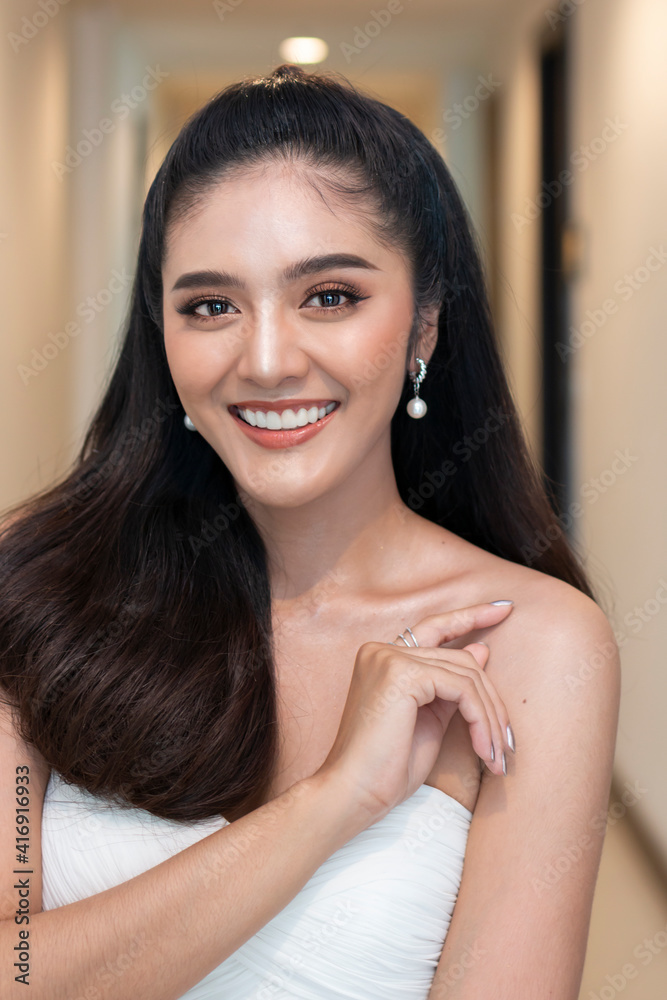 Portrait of casual Asian woman smiling indoor, wearing beautiful makeup and white wedding dress. Young Asian teenage girl on white background posing to the camera at home. Portrait of casual Asian woman smiling indoor, wearing beautiful makeup and white wedding dress. Young Asian teenage girl on white background posing to the camera at home.
