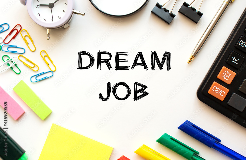 Office desk table with calculator, pens and other stationery. Text on the DREAM JOB. Office desk table with calculator, pens and other stationery. Text on the DREAM JOB.