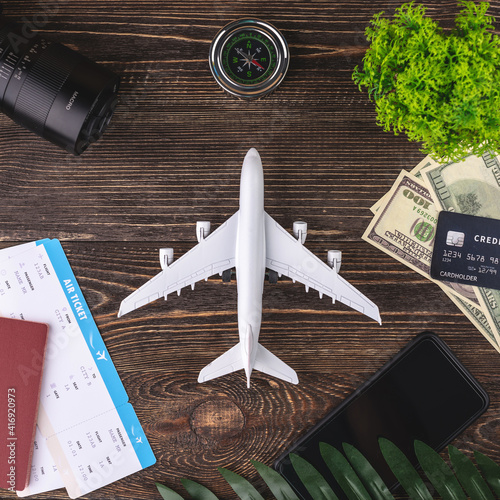 Small plane on a table with tickets, documents, money and other travel accessories. Concept of vacation and booking