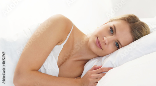 Young and beautiful blond girl in the bed. Sleeping woman in a rays of morning sun.