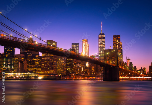 Fototapeta Naklejka Na Ścianę i Meble -  View of Brooklyn Bridge and Manhattan skyline WTC Freedom Tower from Dumbo by night, Brooklyn. Brooklyn Bridge is one of the oldest suspension bridges in the USA