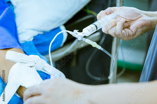 Doctor injecting medicine in infusion by syringe