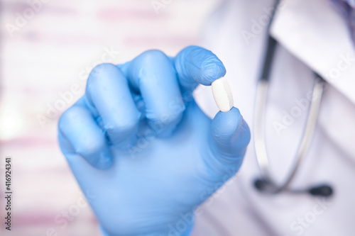 doctor hand in protective glass holding pill close up 