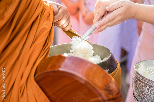 Quadro em tela Woman hand put rice in alms bowl of Buddhist monk on morning