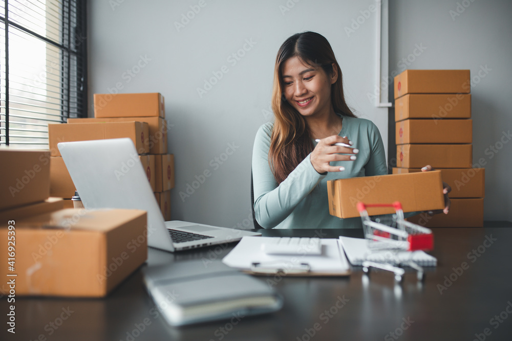 Start up successful small business owner,working from home with laptop computer and online purchase shopping order and box packaging on table (new normal concept) Start up successful small business owner,working from home with laptop computer and online purchase shopping order and box packaging on table (new normal concept)
