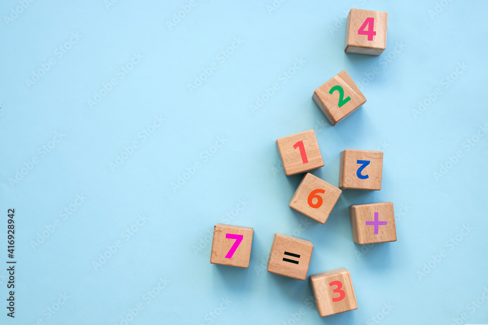 Top view of colorful bricks on turquoise wooden table background. Figures and arithmetic signs. Education concept