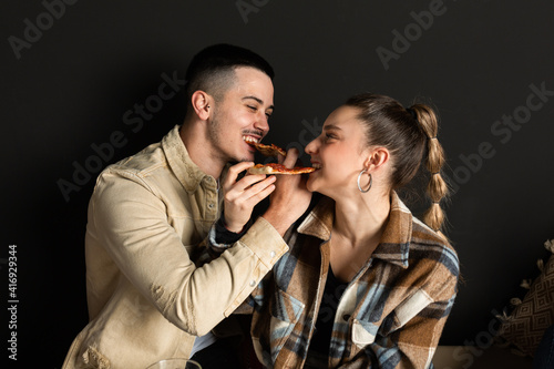 boy and girl couple share 2 slices of pizza by intertwining arms