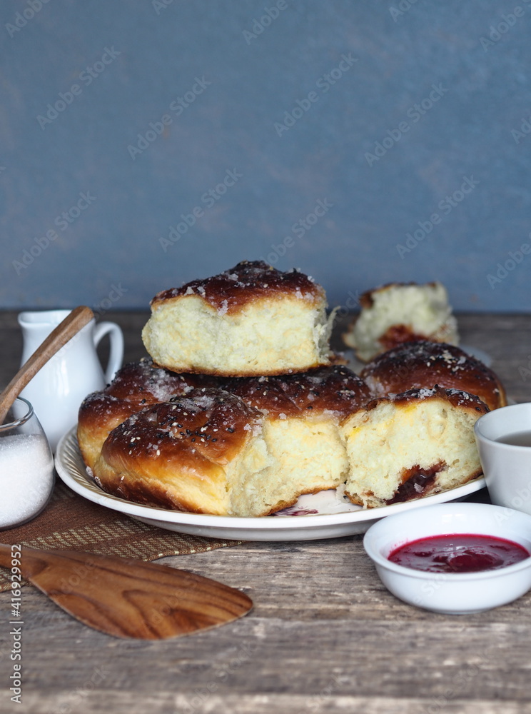 Homemade cake.Buns filled with jam, sprinkled with sesame and icing sugar, on an ancient wooden table, with ingredients and a Cup of tea, with a gray background. Homemade cake.Buns filled with jam, sprinkled with sesame and icing sugar, on an ancient wooden table, with ingredients and a Cup of tea, with a gray background.