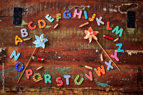 Auburn wooden table with colorful letters that show the alphabet lying in a circle.