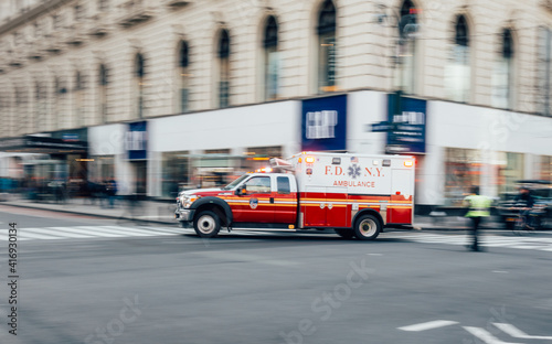 New York City, USA - March 18, 2017: FDNY Ambulance flashing lights siren blasting speed through midtown rush hour traffic in Manhattan. photo