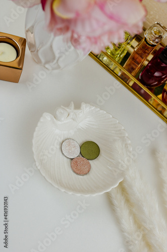 Round white, beige and green blush and eyeshadow on white plate