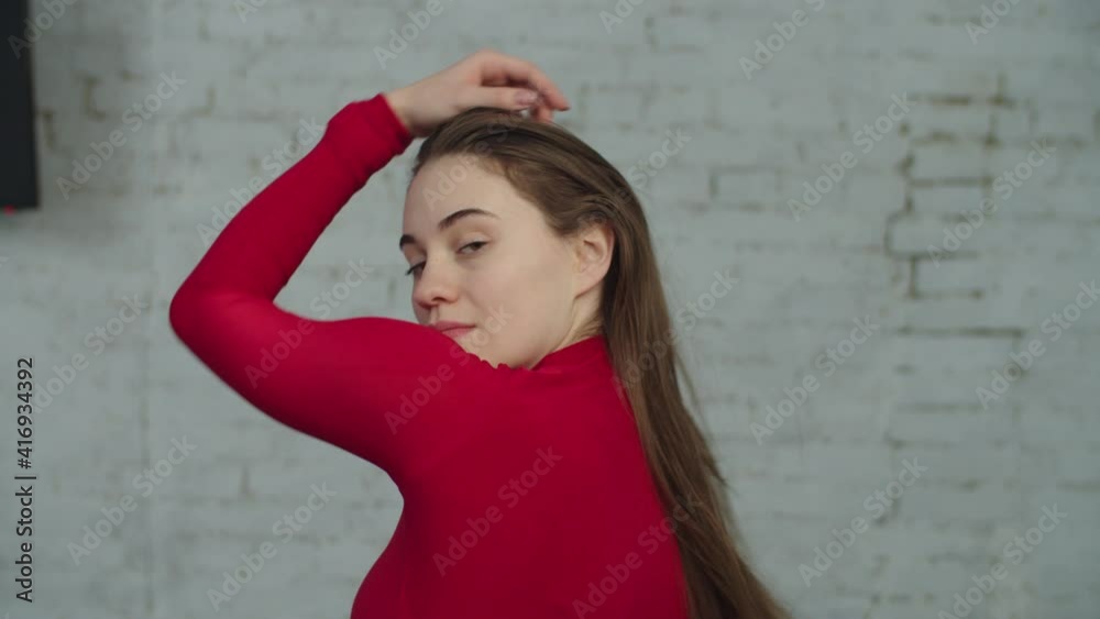Portrait of charming attractive female with long straight hair looking back over shoulder, staring with beckoning flirting expression, showing carefree playful mood, attraction and sensuality indoors. Portrait of charming attractive female with long straight hair looking back over shoulder, staring with beckoning flirting expression, showing carefree playful mood, attraction and sensuality indoors.