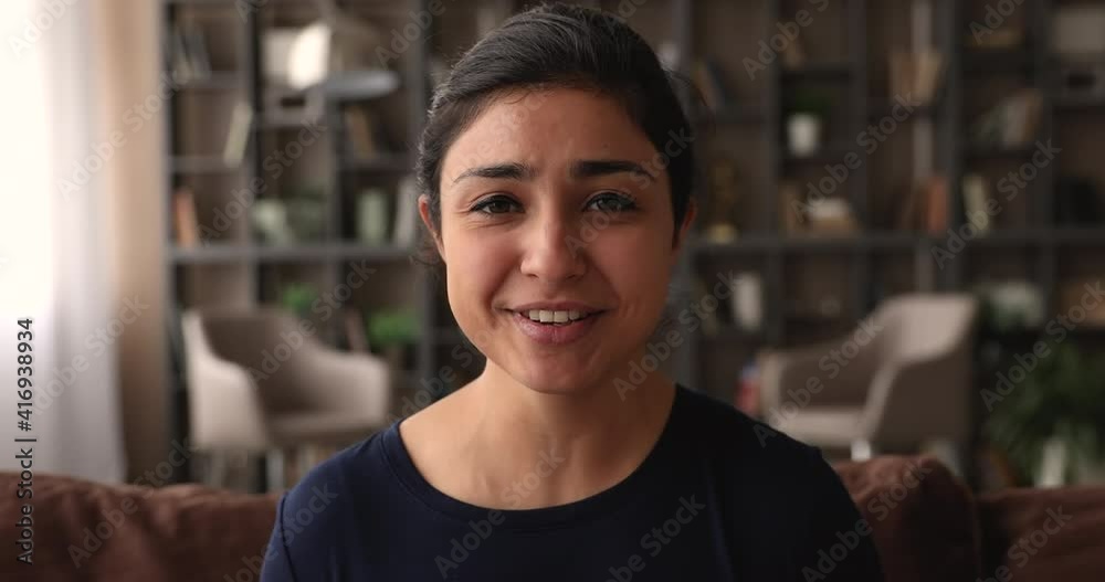 Web camera view beautiful smiling millennial indian ethnicity woman waving hand making hello gesture, starting online video call conversation, talking speaking enjoying distant communication at home.