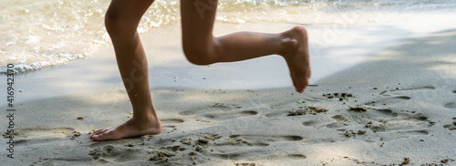 A child runs along the river bank splashing water with his feet. In summer, the child plays on the beach, runs barefoot on the sand. Sea tour. Children's feet in the sand