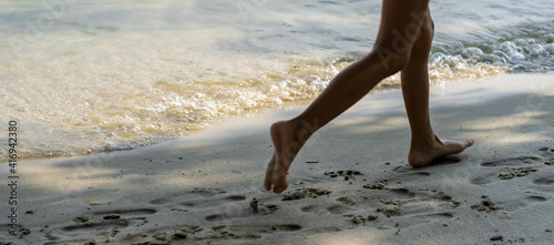 A child runs along the river bank splashing water with his feet. In summer, the child plays on the beach, runs barefoot on the sand. Sea tour. Children's feet in the sand