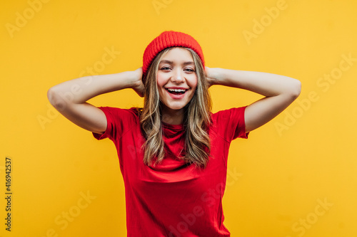 Live emotions! On a yellow background, a girl in red clothes, emotionally smiling at the camera, photo for advertising © Тарас Нагирняк