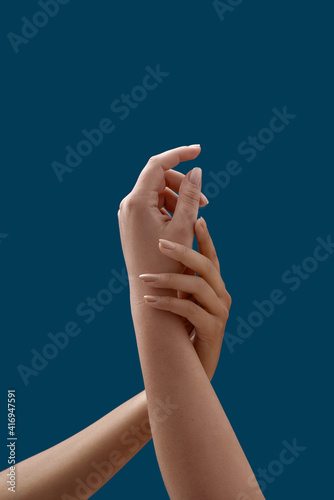 Close up of two female hands embracing each other isolated on blue background