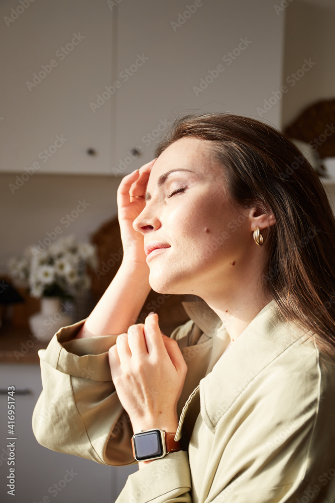 Woman with natural freckles enjoying morning sunlight on kitchen in her eco house. Indoor portrait of Millennial brunette woman Woman with natural freckles enjoying morning sunlight on kitchen in her eco house. Indoor portrait of Millennial brunette woman