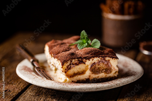 Piece of traditional Italian dessert tiramisu on dark background photo