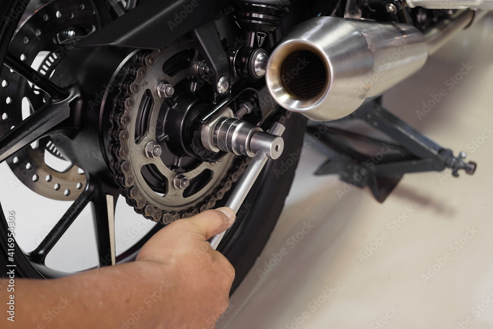 mechanic using a wrench and socket fixing motorbike in motorcycle