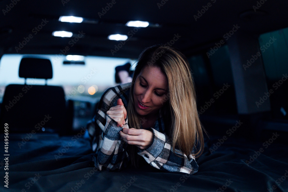 Happy blonde woman lying on bed in camper van Happy blonde woman lying on bed in camper van