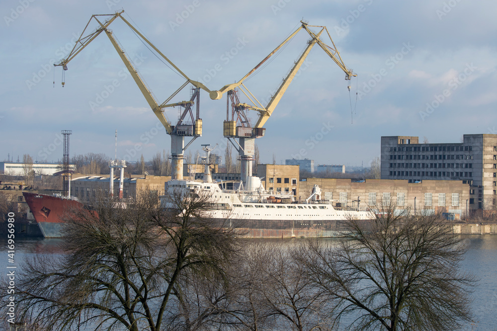 View of the shipyard. Two tower cranes and a ship hull. View of the shipyard. Two tower cranes and a ship hull.