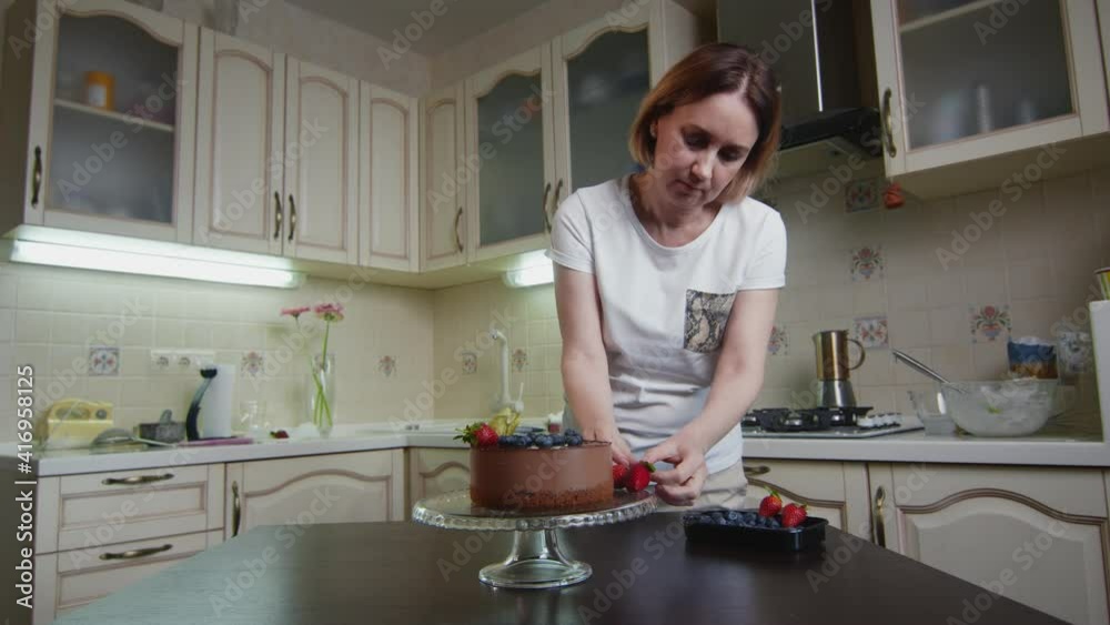 Housewife woman decorates the chocolate cake with berries Housewife woman decorates the chocolate cake with berries