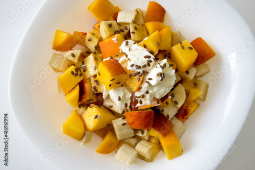 Healthy nutrition fruit salad with soft cheese and flax seeds in white bowl. Low calories desserts. Natural organic food. Light healthy lunch, tasty simple snack.