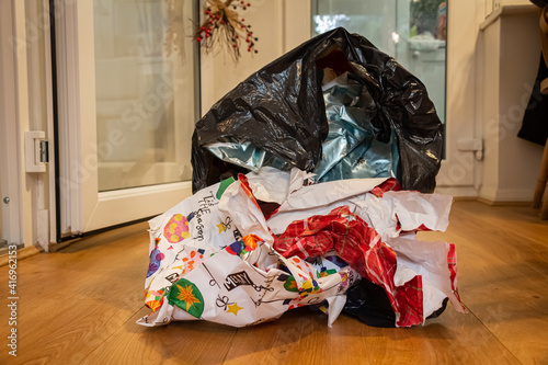 Christmas wrapping paper waste in a bin liner lying on a wooden floor