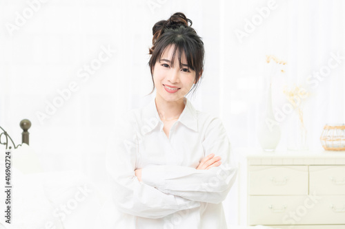 部屋で腕組みをしている白いシャツを着た若い女性