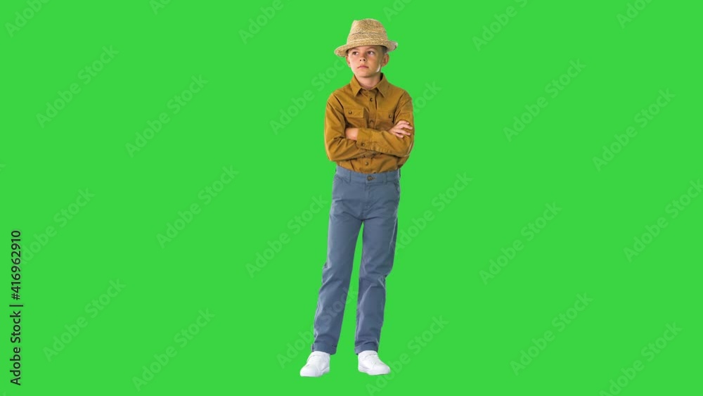 Boy in a shirt and straw hat posing with crossed arms and then putting arms on his hips on a Green Screen, Chroma Key. Boy in a shirt and straw hat posing with crossed arms and then putting arms on his hips on a Green Screen, Chroma Key.