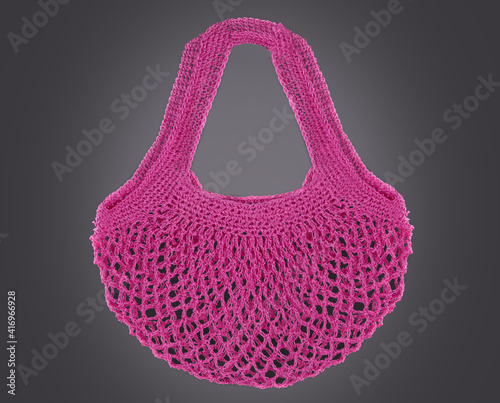 Handmade pink string bag on grey background. Close-up. Raffia bag. Wicker bag.