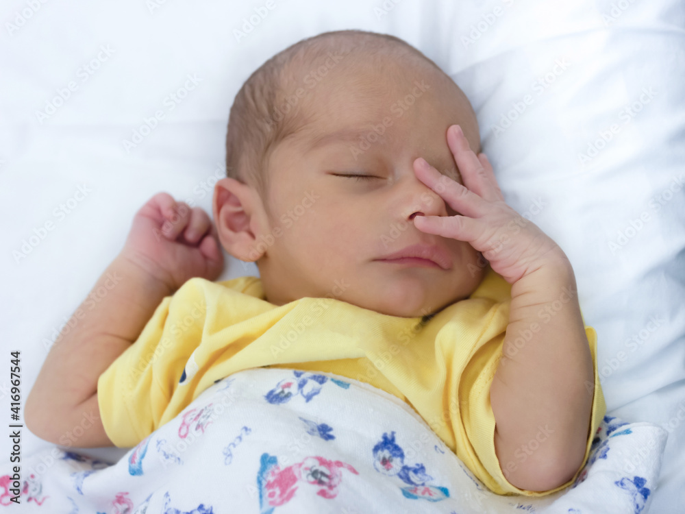 Very cute newborn baby sleeping on the bed with hands near face Very cute newborn baby sleeping on the bed with hands near face