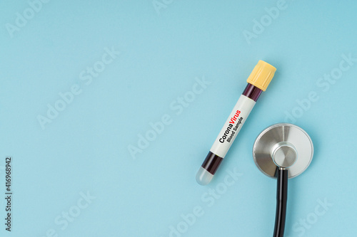 Stethoscope and blood sample vacuum tube on blue background. Corona virus concept with a copy space.