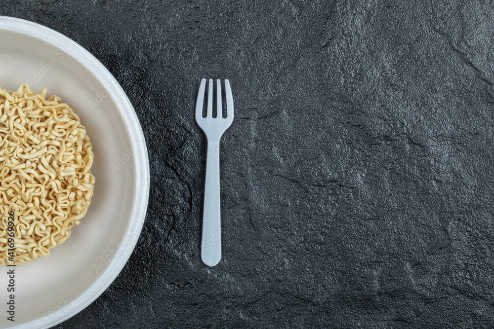 Plate of unprepared noodles on a dark background Plate of unprepared noodles on a dark background