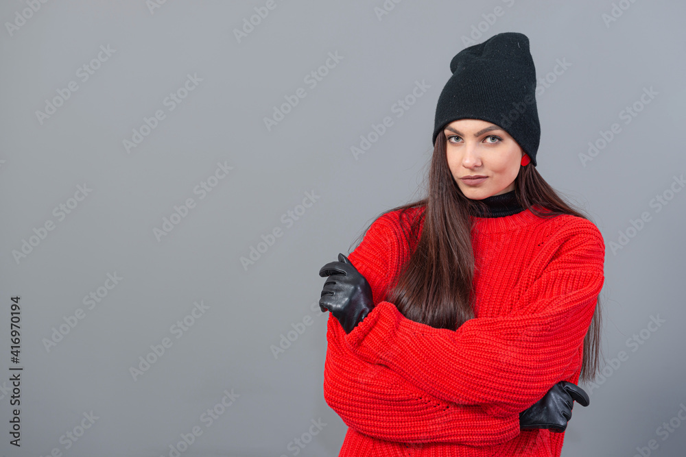 teenage female with a black winter hat and leather gloves, dressed in a red sweater, isolated on gray teenage female with a black winter hat and leather gloves, dressed in a red sweater, isolated on gray
