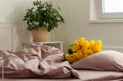 On the bed is a bouquet of yellow tulips. Bouquet of fresh tulips. Spring flowers in the bedroom interior. The concept of spring or holiday, March 8, International Women's Day