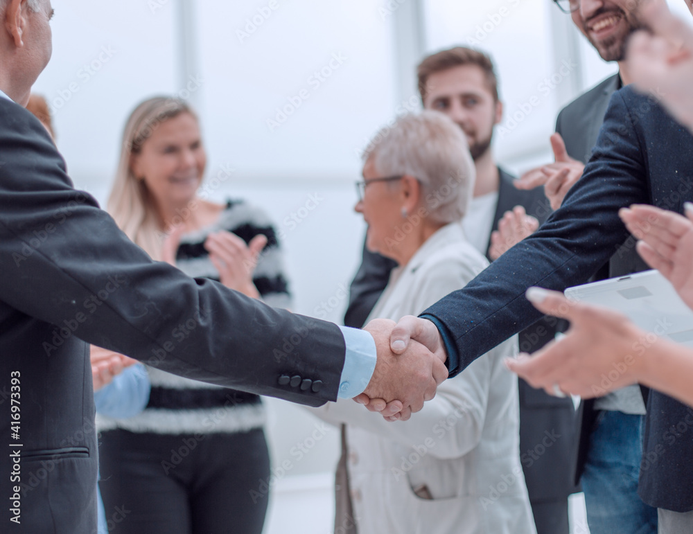 Two business people shaking hands in front of their colleagues Two business people shaking hands in front of their colleagues