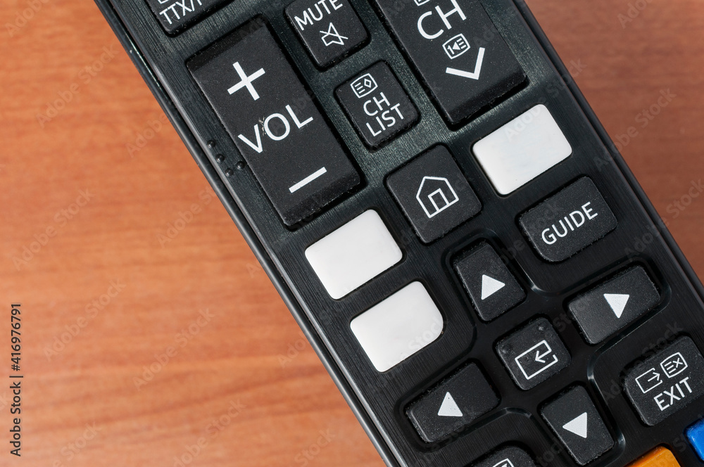 Tv remote control with white bank buttons for on demand services logos on a wooden table Tv remote control with white bank buttons for on demand services logos on a wooden table