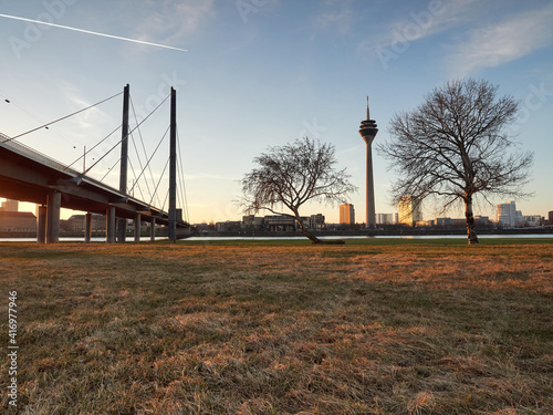 The Rheinknie bridge and the Rheinturm tower in the city of Dusseldorf during sunrise. View of the city skyline from the bank of the river Rhine photo