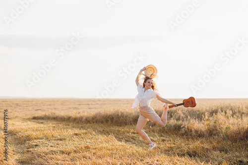 Girl with long curly hair poses in a wheat field