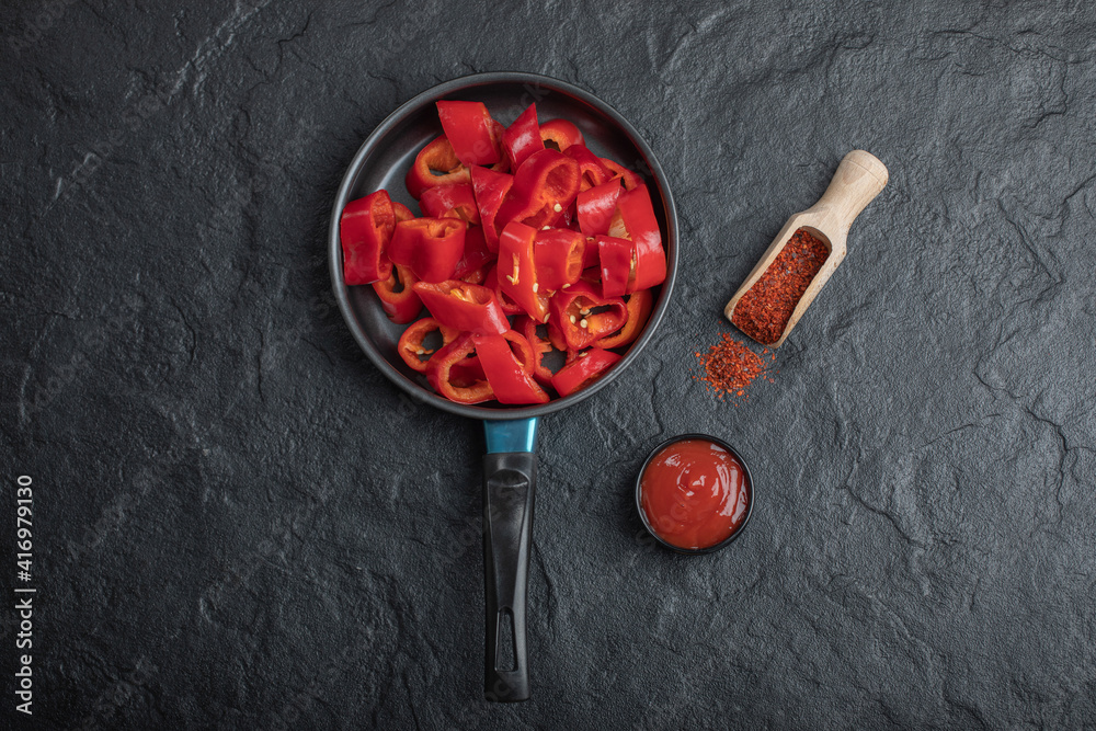 Pan of sliced red bell peppers with ground pepper and ketchup Pan of sliced red bell peppers with ground pepper and ketchup