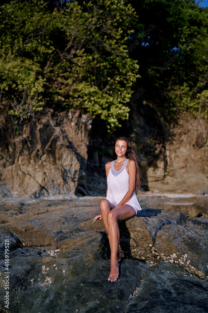 Outdoor portrait of beautiful young woman with long hair sitting on the rock. Outdoor portrait of beautiful young woman with long hair sitting on the rock.