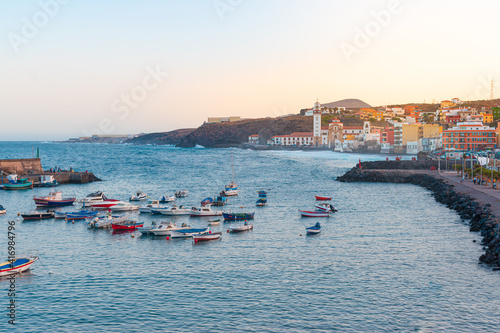 Scenic view of Candelaria's harbor and cathedral in the evening in Tenerife, Spain, with small boats tied