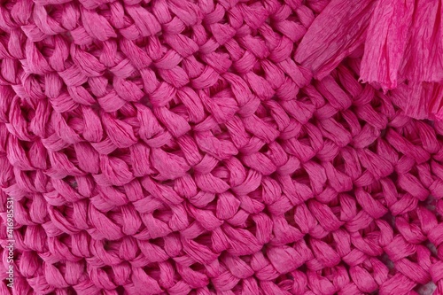 Handmade pink  raffia bag on grey background. Close-up. Wicker bag. Pink  wickerwork.