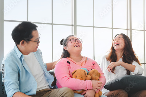 Happy asian family sitting on sofa and playing dolls with their daughter down syndrome child in living room at morning time, Activity happy family lifestyle concept,