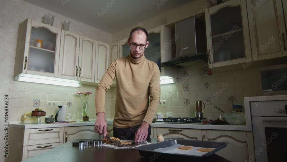 Male chef man puts cut out gingerbread cookies on baking sheet Male chef man puts cut out gingerbread cookies on baking sheet