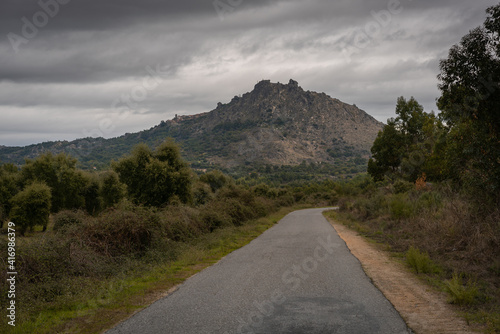 Narrow road on a cloudy day with landscape view of a mountain hill of Monsanto, in Portugal